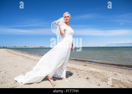 Mariée en robe de mariage standing on beach Banque D'Images