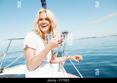 Young woman using smart phone sur voilier, Mer Adriatique Banque D'Images