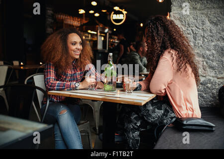 Deux jeunes femmes parlant assis dans un restaurant. African woman smiling et discutant avec son ami dans un café. Banque D'Images