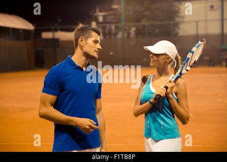 Portrait d'une femme qui parle avec son entraîneur personnel de tennis extérieur Banque D'Images