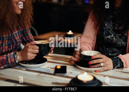 Cropped shot of two women sitting holding tasse de café. Les amis de boire du café à une table Banque D'Images