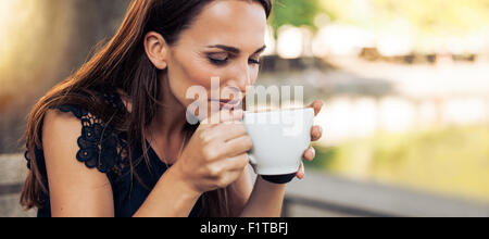 Portrait de jeune femme avec un café aromatique dans les mains. Femme de boire du café au café. Banque D'Images