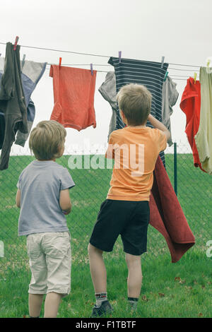 Deux jeunes garçons étendre le linge sur une corde. Banque D'Images