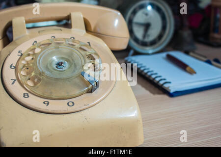Téléphone à cadran et livre sur une table en bois. Banque D'Images