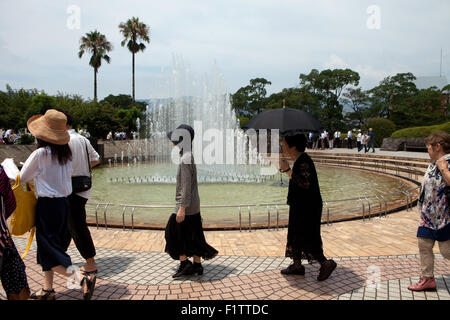 Les gens à l'occasion du 70e anniversaire du bombardement atomique de Nagasaki en 1945 à pied de la fontaine de la paix dans le parc de la paix, au Japon Banque D'Images