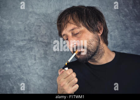 Portrait d'homme adultes occasionnels allumer une cigarette Banque D'Images