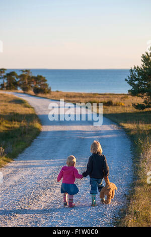 Jeune fille blonde et garçon main dans la main sur un chemin, Gotland, Suède, modèle libération Banque D'Images