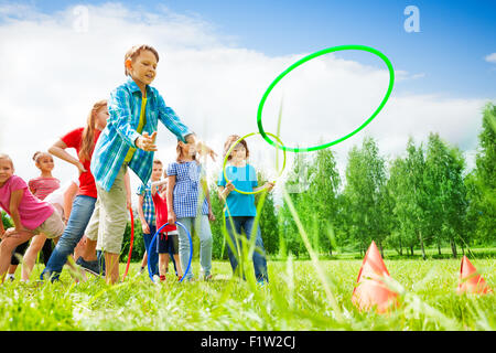 Enfants jouant et jetant des cercles colorés Banque D'Images