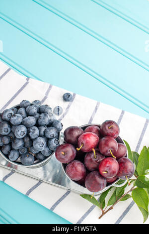 Les prunes, et les bleuets en petit seau en métal sur la table en bois. Banque D'Images