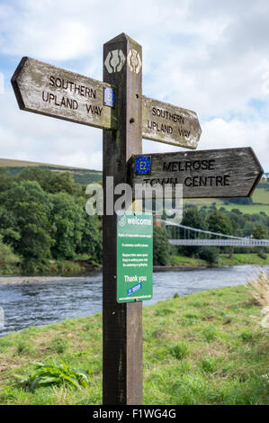 Le sud de l'Upland Way marcheurs signpost with Chainbridge en arrière-plan. Sur la rivière Tweed à Melrose, Scottish Borders, R.-U. Banque D'Images