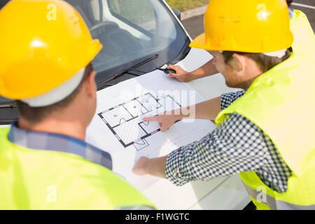 Close up de constructeurs avec le plan sur un capot de voiture Banque D'Images