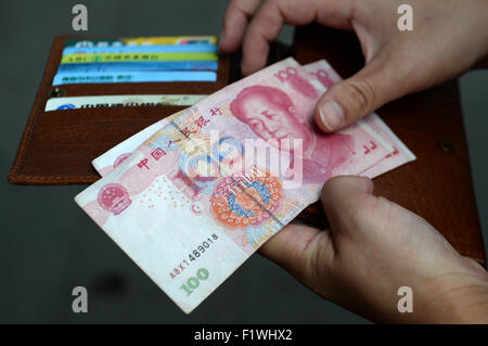 Shanghai, Chine. Août 30, 2015. Une femme est titulaire d'yuan chinois billets dans la monnaie chinoise renminbi et un portefeuille avec plusieurs cartes de crédit et le téléphone dans ses mains à Shanghai, Chine, 30 août 2015. Photo : Jens Kalaene/dpa/Alamy Live News Banque D'Images