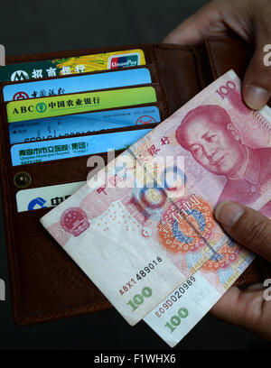 Shanghai, Chine. Août 30, 2015. Une femme est titulaire d'yuan chinois billets dans la monnaie chinoise renminbi et un portefeuille avec plusieurs cartes de crédit et le téléphone dans ses mains à Shanghai, Chine, 30 août 2015. Photo : Jens Kalaene/dpa/Alamy Live News Banque D'Images