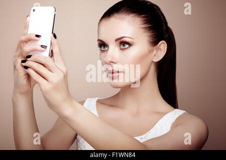 Belle jeune femme prendre. selfies Elle-même fille de photographier avec téléphone. Beauty fashion. Les cils. Ombre à paupières cosmétique Banque D'Images