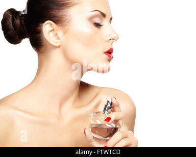 Young woman applying perfume sur elle-même isolé sur fond blanc. Photo de Mode Banque D'Images