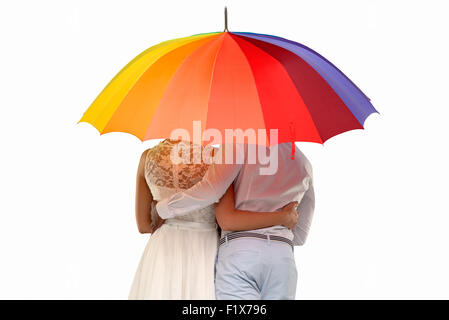 Trois quart Vue arrière d'un couple romantique sous un parapluie coloré, isolated on white Banque D'Images