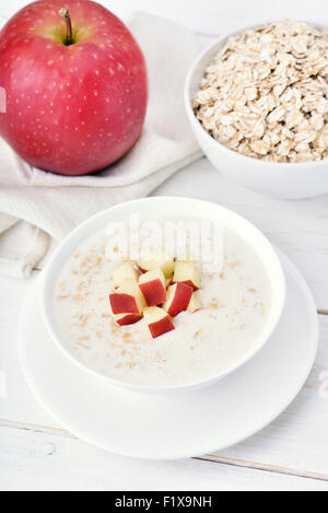 Avec porridge tranches de pomme rouge sur une table en bois blanc Banque D'Images