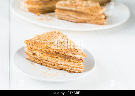 Maison medovik (morceau de gâteau de miel en couches, Gâteau traditionnel russe) avec de la Crème et caramel sur plaque blanche sur tableau blanc Banque D'Images