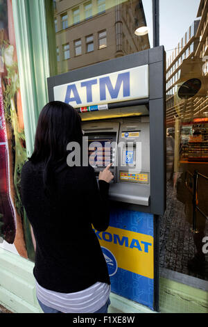 Jeune femme à l'aide d'un guichet automatique pour retirer de l'argent Banque D'Images