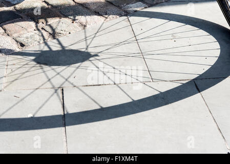 Ombre d'un cycle pneu sur la chaussée à la gare de Kings Cross, London Banque D'Images