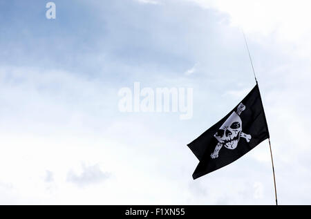 Drapeau pirate dans le vent avec fond de ciel bleu nuageux Banque D'Images