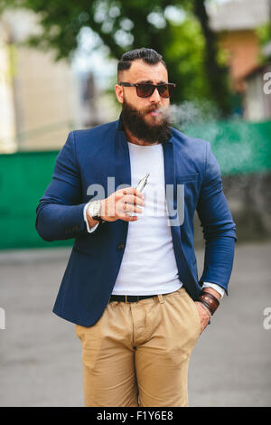 Homme avec une barbe fume cigarette électronique Banque D'Images