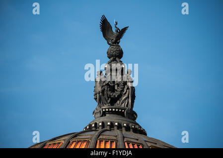 Palacio de Bellas Artes Dome sculptures Mexico // MEXICO CITY, MEXICO — les figures sculpturales ornant le dôme principal du Palacio de Bellas Artes présentent le symbole national du Mexique, un aigle, couronnant une série de statues représentant les arts dramatiques Ce monument culturel du début du XXe siècle abrite le Théâtre national et l'Opéra du Mexique, alliant des éléments extérieurs néoclassiques et Art nouveau à un intérieur Art déco. Le palais est le premier lieu du Mexique pour des spectacles et des expositions d'arts plastiques. La construction a commencé en 1904 sous l'architecte italien Adamo Boari et a été achevée Banque D'Images