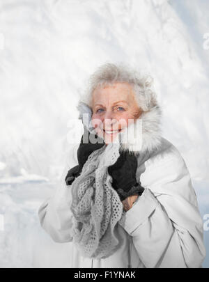 Smiling woman standing in snow s'étire jusqu'à son écharpe en laine et col fourrure sur une froide journée d'hiver, MN, USA Banque D'Images