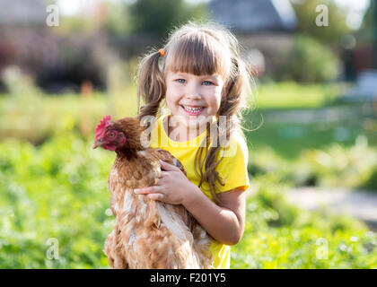 Petite fille avec une poule dans la cour avant Banque D'Images