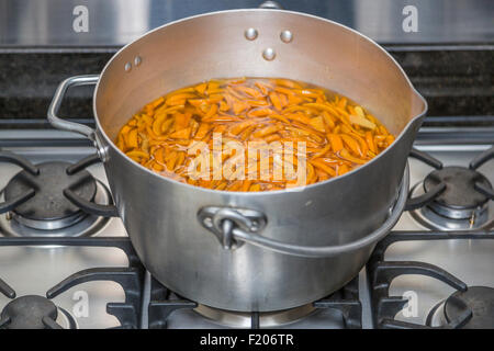 Panneaux oranges pelées dans un métal chauffage préservant le moule sur une cuisinière à gaz en préparation à ébullition pour faire de la marmelade faite maison Banque D'Images