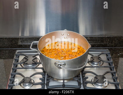 Panneaux oranges pelées dans un métal chauffage préservant le moule sur une cuisinière à gaz en préparation à ébullition pour faire de la marmelade faite maison Banque D'Images