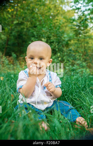 Heureux, smiling baby sur l'herbe verte dans le parc Banque D'Images