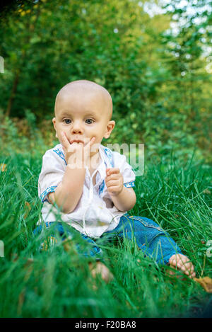 Beau bébé dans la broderie sur l'herbe verte dans le parc Banque D'Images