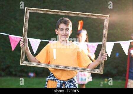 Portrait of boy looking through photo frame, looking at camera Banque D'Images