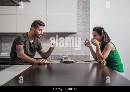 Jeune couple en face de l'autre de prendre le petit déjeuner dans la cuisine Banque D'Images