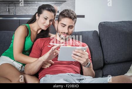 Jeune couple on sofa using digital tablet Banque D'Images