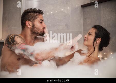 Jeune couple jouant avec des bulles dans le bain de mousse Banque D'Images