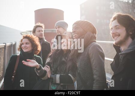 Six jeunes amis adultes bavarder et rire sur passerelle Banque D'Images