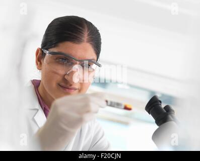 Jeune femme scientifique affichage des échantillon de sang au cours de l'essai clinique d'échantillons médicaux dans un laboratoire Banque D'Images