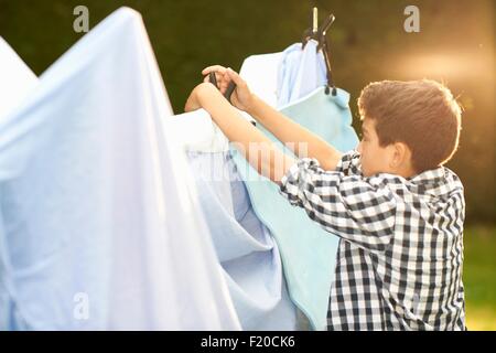 Boy putting draps sur des tente dans jardin Banque D'Images