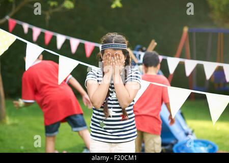 Girl couvrant ses yeux pour cache-cache avec les frères dans le jardin Banque D'Images