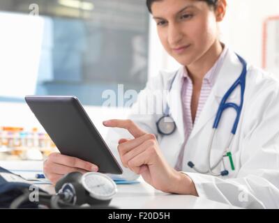 Femme médecin mise à jour des dossiers médicaux sur tablette numérique Banque D'Images