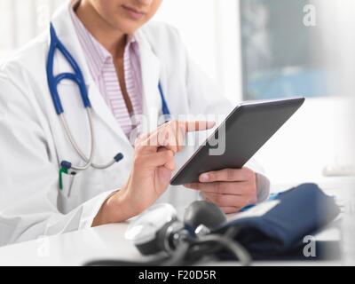 Cropped shot of female doctor using digital tablet écran tactile pour mettre à jour les dossiers médicaux Banque D'Images