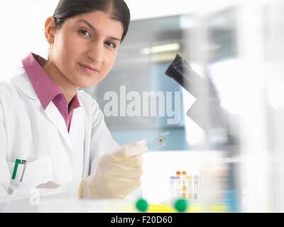 Portrait of female scientist testing des échantillons de sang à l'aide de microscope Banque D'Images
