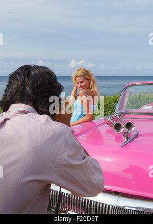 Jeune femme qui pose pour des photos avec vintage convertible, La Havane, Cuba Banque D'Images