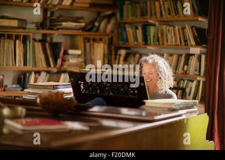 Young woman smiling tout en jouant du piano dans la salle de séjour Banque D'Images