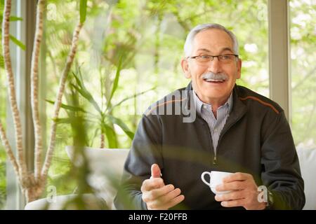 Senior à la maison, boire du café Banque D'Images