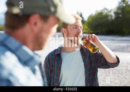 Jeune homme de prendre un verre d'une bouteille de bière, à l'écart Banque D'Images