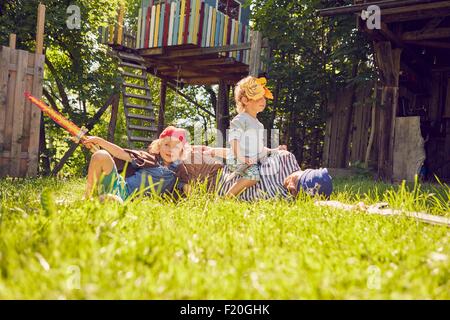 Son père et ses deux fils dans le jardin, portant les costumes, jouant avec la prétention swords Banque D'Images