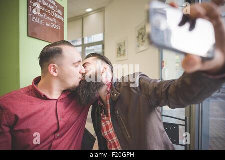 Couple Gay en tenant et selfies kissing in cafe Banque D'Images